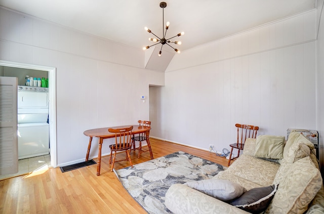 living area featuring a notable chandelier, stacked washer / drying machine, and wood finished floors