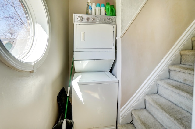 washroom with stacked washer and clothes dryer and laundry area