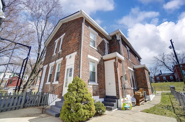 view of property exterior featuring fence and brick siding