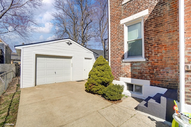 exterior space featuring fence, driveway, an outdoor structure, a garage, and brick siding