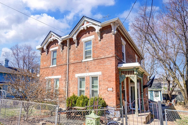 view of front of home featuring a gate, brick siding, and a fenced front yard