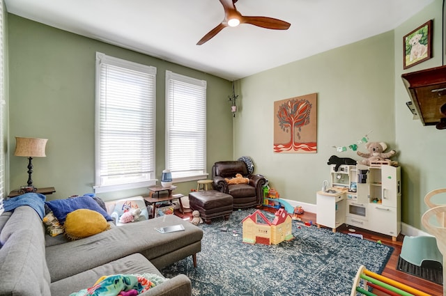 living area with ceiling fan, baseboards, and wood finished floors