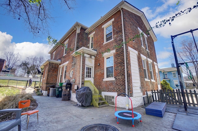 back of property with brick siding, a patio, and fence