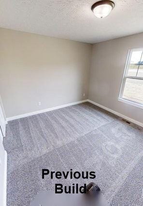 spare room with visible vents, a textured ceiling, carpet, and baseboards