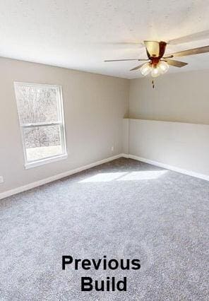 carpeted spare room with a ceiling fan and baseboards