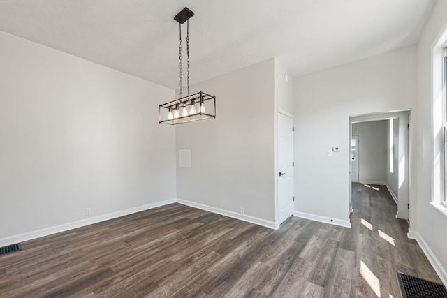 unfurnished dining area featuring dark wood-style floors, visible vents, a notable chandelier, and baseboards