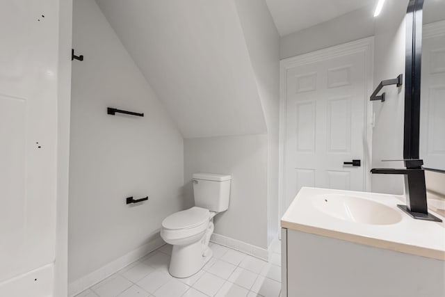 bathroom with vanity, baseboards, tile patterned flooring, vaulted ceiling, and toilet