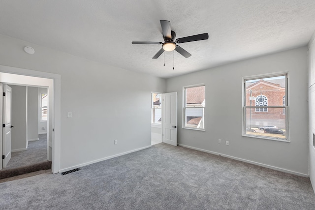 unfurnished bedroom featuring baseboards, visible vents, carpet floors, and a textured ceiling