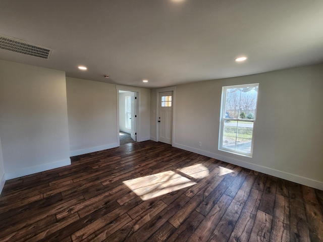 spare room featuring dark wood-type flooring, recessed lighting, baseboards, and visible vents