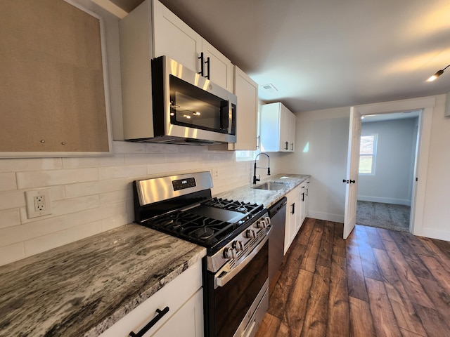 kitchen featuring backsplash, light stone countertops, appliances with stainless steel finishes, and a sink