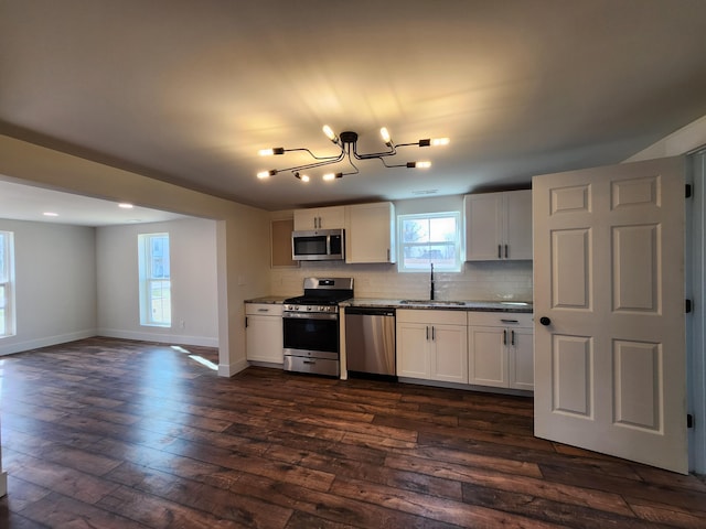 kitchen featuring dark wood-type flooring, a sink, tasteful backsplash, white cabinetry, and stainless steel appliances