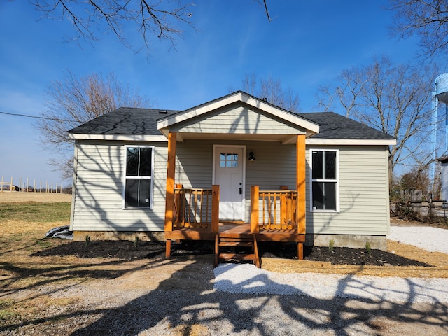 rear view of house with roof with shingles and a porch