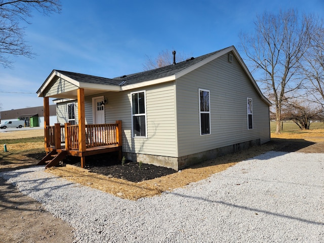 view of side of property featuring roof with shingles and gravel driveway