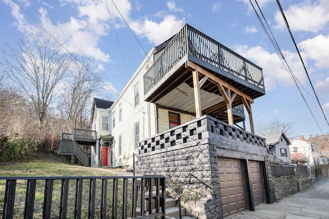 view of side of property featuring stairs, a wooden deck, a lawn, and an attached garage