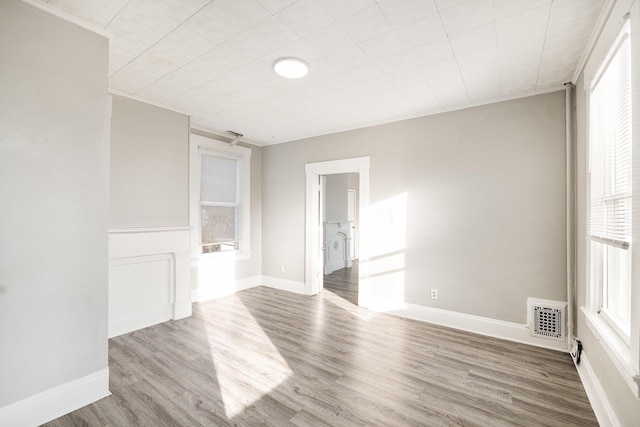 spare room with wood finished floors, visible vents, and baseboards