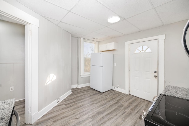 foyer entrance with baseboards, a paneled ceiling, and light wood-style floors