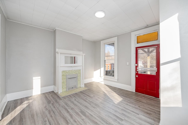 unfurnished living room with ornamental molding, a fireplace, baseboards, and wood finished floors