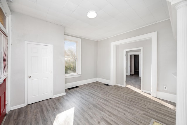 spare room featuring visible vents, baseboards, and wood finished floors