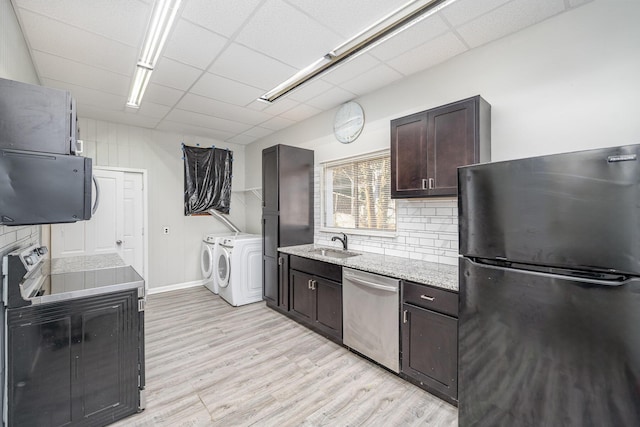 kitchen featuring a sink, stainless steel dishwasher, freestanding refrigerator, separate washer and dryer, and dark brown cabinetry