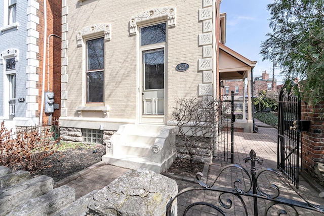 view of exterior entry with brick siding and a gate