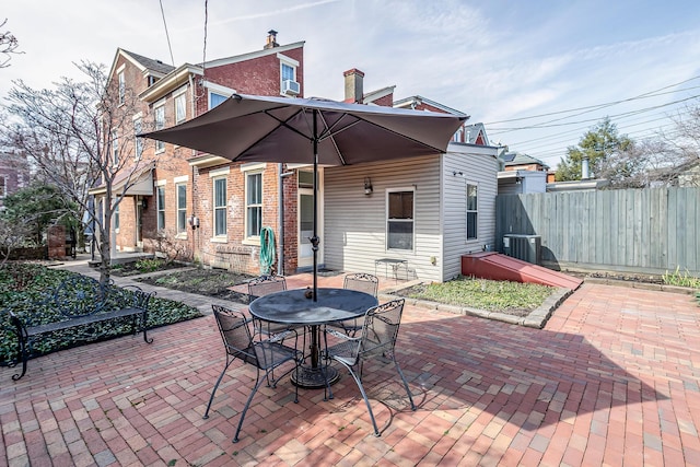 rear view of house featuring cooling unit, a patio, brick siding, and fence