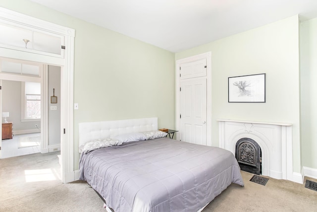 carpeted bedroom featuring baseboards and a fireplace with flush hearth