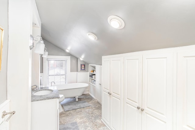 full bathroom featuring vanity, lofted ceiling, a freestanding tub, and wainscoting