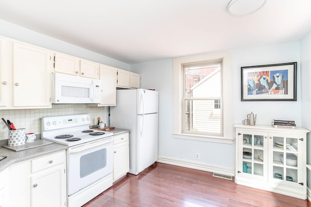 kitchen with visible vents, backsplash, white appliances, and light countertops