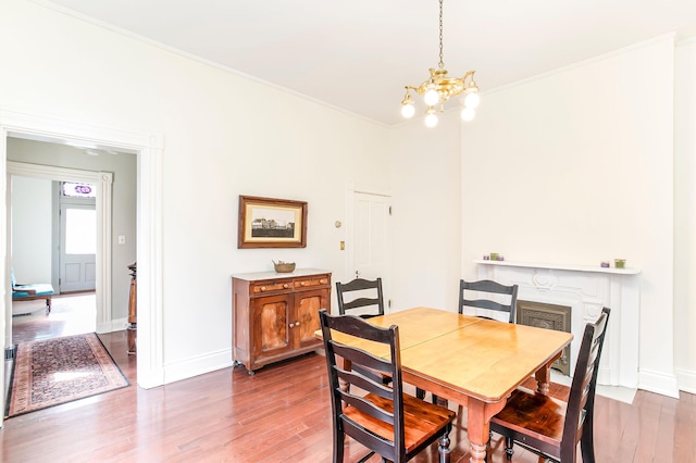 dining room with a chandelier, ornamental molding, baseboards, and wood finished floors