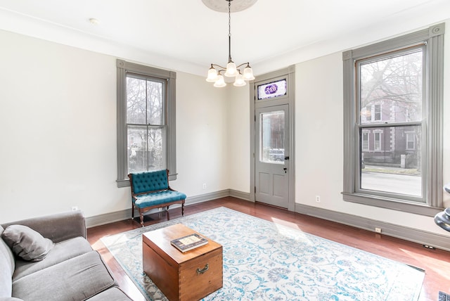 living area with a notable chandelier, baseboards, and wood finished floors