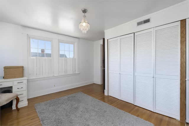 interior space featuring visible vents, baseboards, wood finished floors, and a chandelier