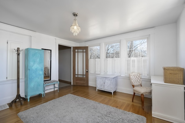 sitting room featuring visible vents, baseboards, an inviting chandelier, and wood finished floors