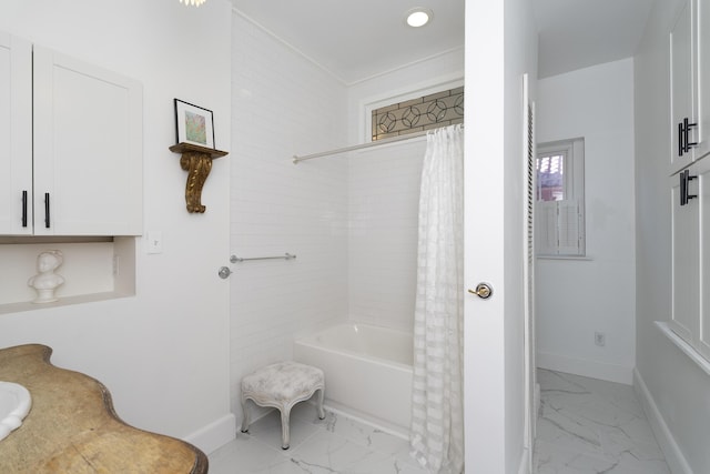 bathroom featuring marble finish floor, baseboards, and shower / bath combo