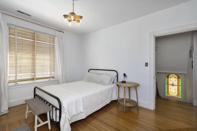 bedroom featuring visible vents, multiple windows, baseboards, and wood finished floors