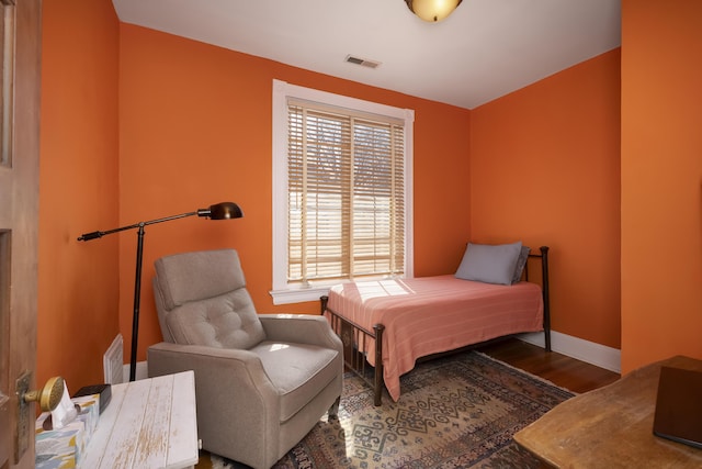 bedroom with visible vents, baseboards, and wood finished floors