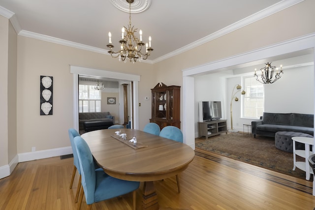 dining room with ornamental molding, light wood-style floors, and a chandelier