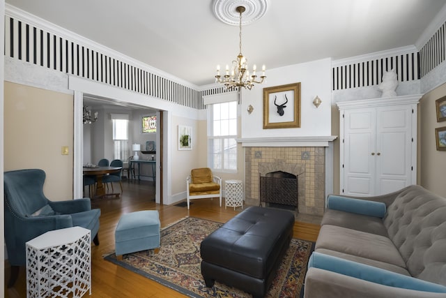 living room featuring baseboards, a notable chandelier, wood finished floors, and a tiled fireplace