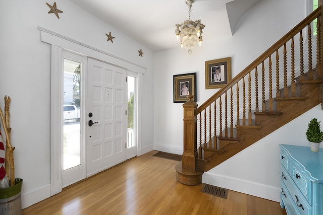 entrance foyer with visible vents, a notable chandelier, light wood-style floors, baseboards, and stairs