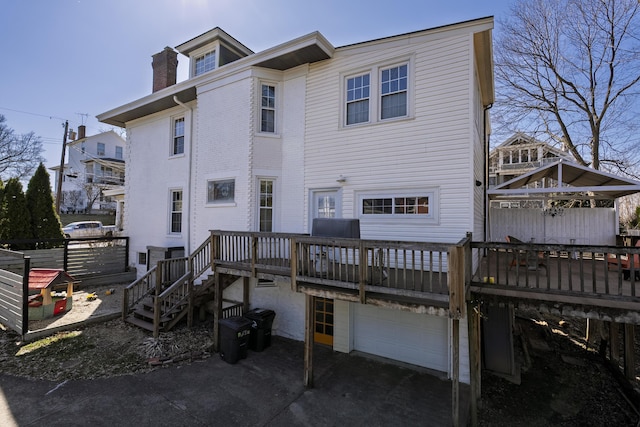 rear view of house featuring an attached garage, a deck, and a chimney