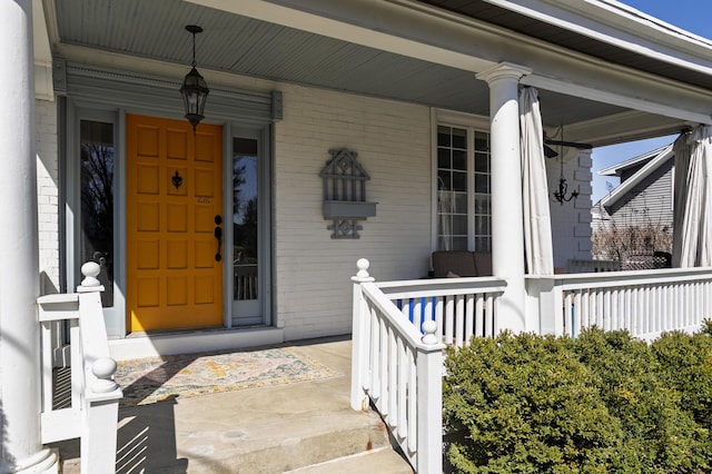 doorway to property featuring brick siding and covered porch