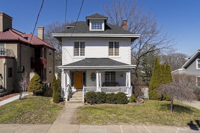 traditional style home featuring a shingled roof, a porch, a front lawn, and a chimney