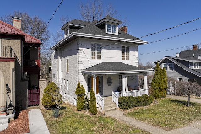 traditional style home featuring a porch, a front yard, and a shingled roof