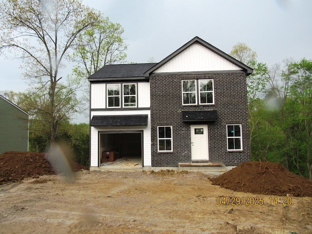 modern farmhouse style home featuring brick siding, an attached garage, and driveway