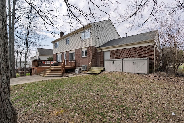 rear view of house with central AC unit, a chimney, a deck, a lawn, and brick siding