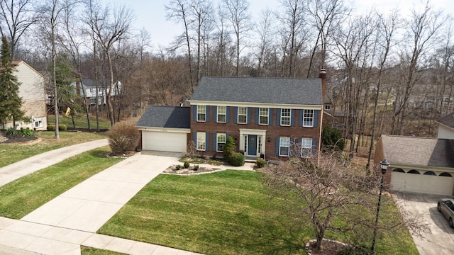 view of front of house featuring concrete driveway, a front yard, a garage, brick siding, and a chimney