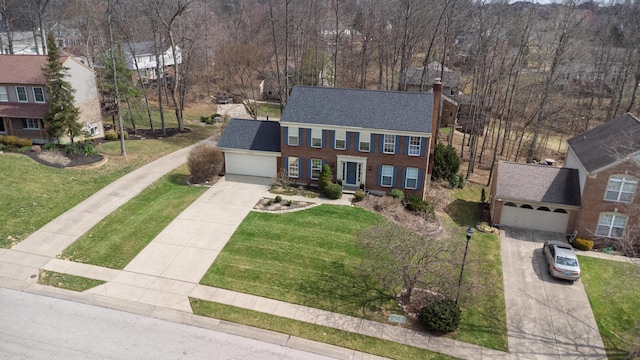 view of front of home with a front yard, roof with shingles, an attached garage, a chimney, and concrete driveway