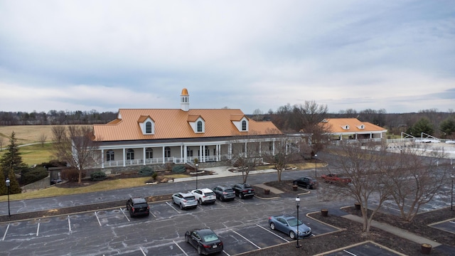 rear view of property featuring uncovered parking, covered porch, and metal roof