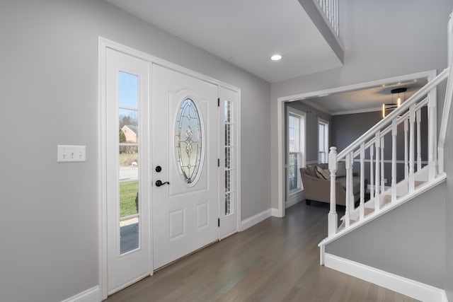 foyer entrance with a wealth of natural light, stairway, baseboards, and wood finished floors