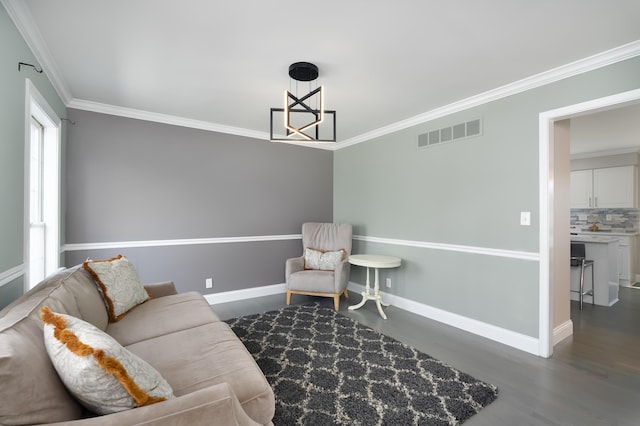 living area with visible vents, crown molding, baseboards, and wood finished floors