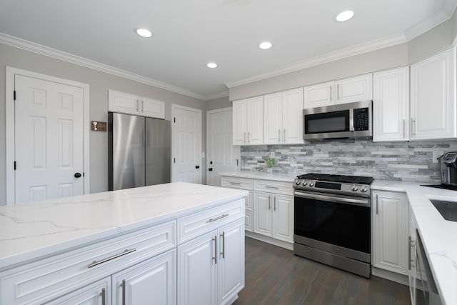 kitchen with light stone counters, white cabinetry, stainless steel appliances, and crown molding